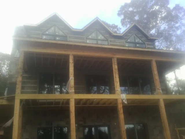 Dormers and porch framing on a large log home under construction — Roof Coating work by our crew in Red Lodge