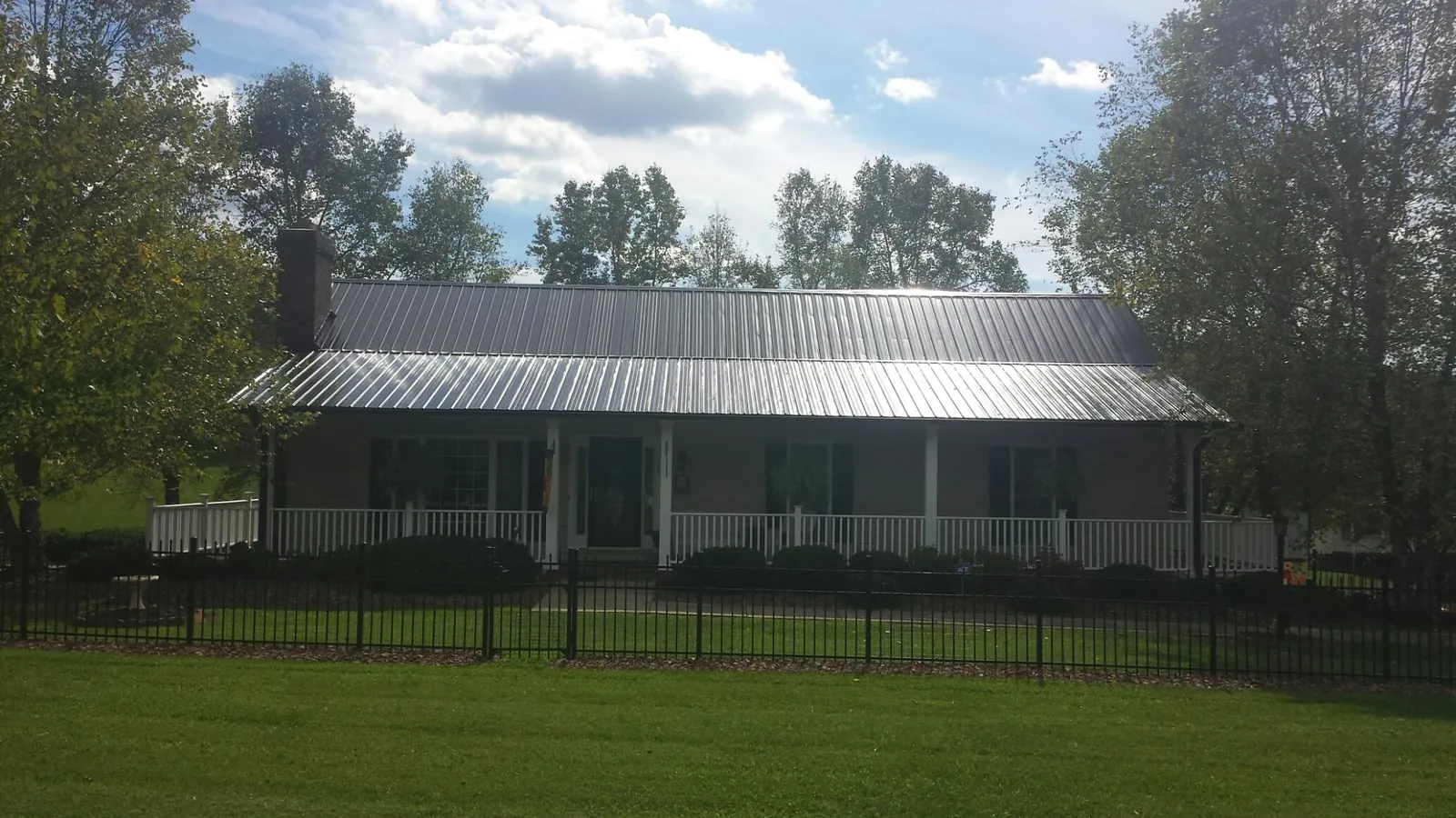 Gray metal roof on a brick ranch with a full width front porch — Gutter Guard Installation work by our crew in Red Lodge