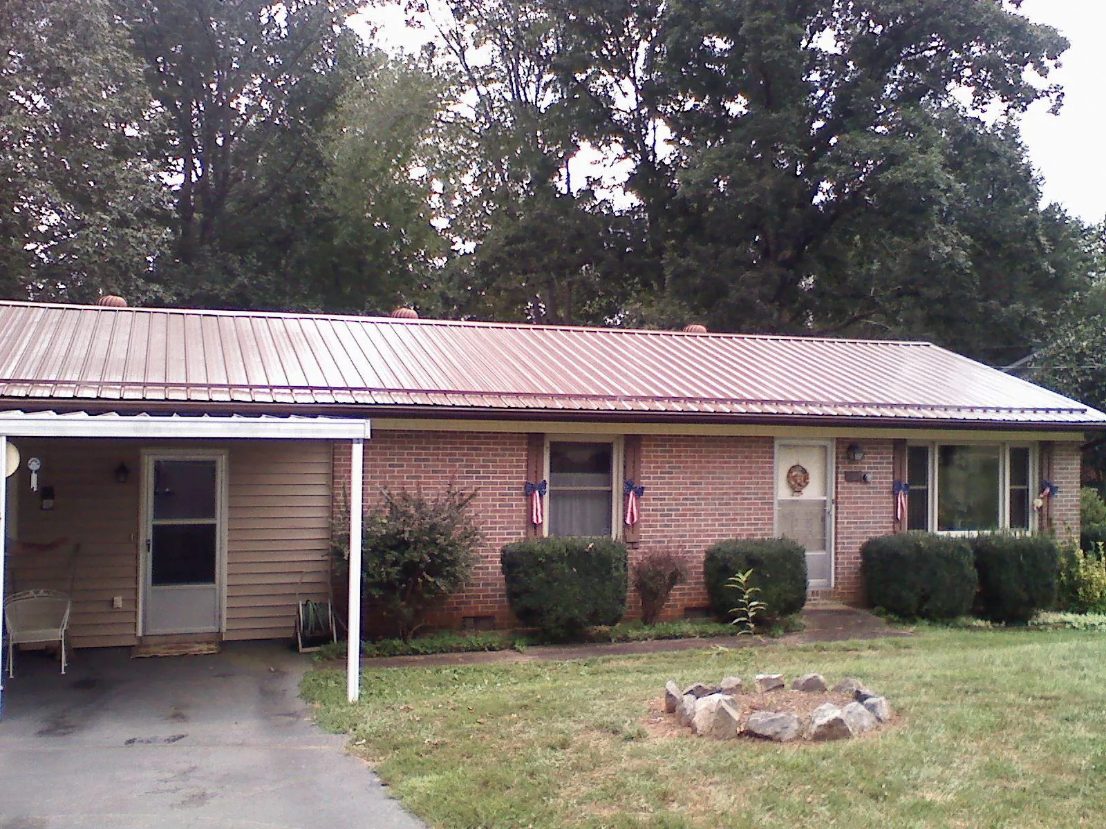 Bronze metal roof and carport on a brick ranch home — Roof Repair work by our crew in Red Lodge