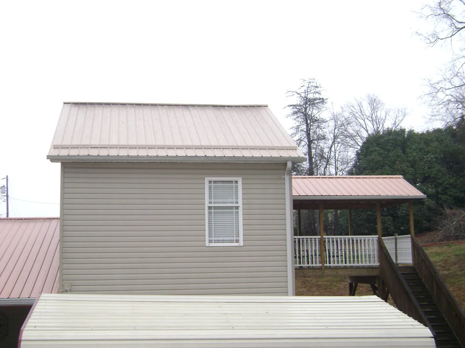 Tan metal roofs on a two story addition and attached porch, from a Roof Replacement job in Red Lodge