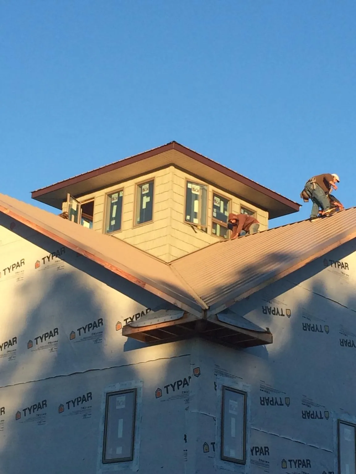 Roofers working around a rooftop cupola on a new metal roof at sunset — Roof Waterproofing in Red Lodge by Roofing Brothers